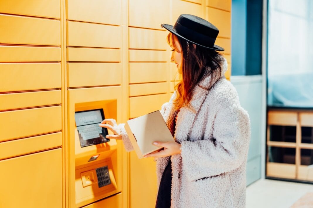 Fashion woman with box using modern postal automatic mail terminal with self service device for pickup or refund an order. Electronic locker for storing parcels. Online shopping. Selective focus